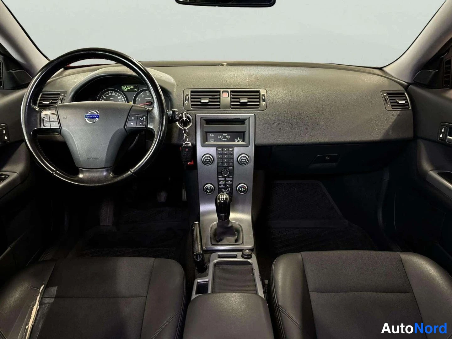 Edestä: Suora näkymä Volvo C30:n kojelautaan: ohjauspyörä, mittaristo, keskikonsoli ja manuaalivaihdekeppi.