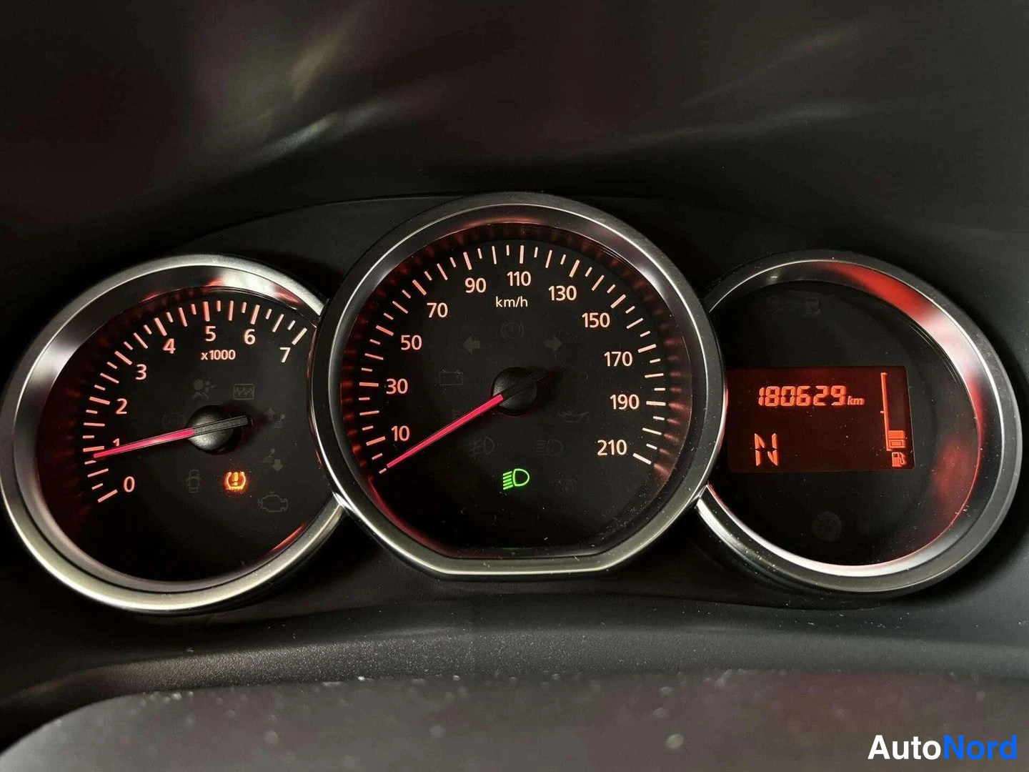 Yksityiskohta: Auton kojelaudan mittaristo: nopeusmittari asteikolla 10–210 km/h, elektroninen näyttö näyttää matkamittarin lukeman 180629 km ja vaihteen N.