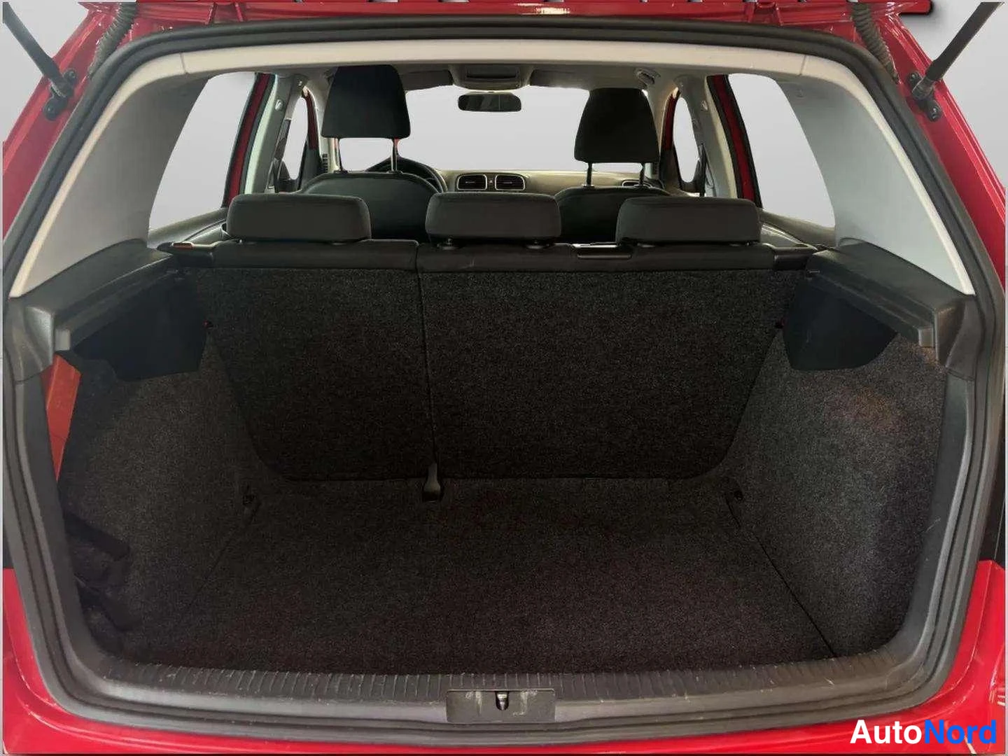 Takaa: Volkswagen Golf 2011 punaisen auton tavaratila takaluukku auki, tumma mattapinta ja taitettu takapenkku