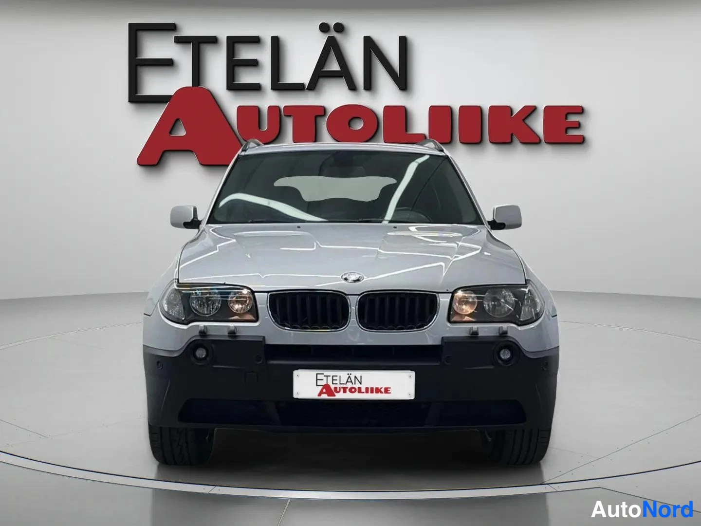 Edestä: BMW X1:n etupään suora kuva hopeanvärisenä studiotyylisellä taustalla, Etelän Autoliike -logo taustalla.