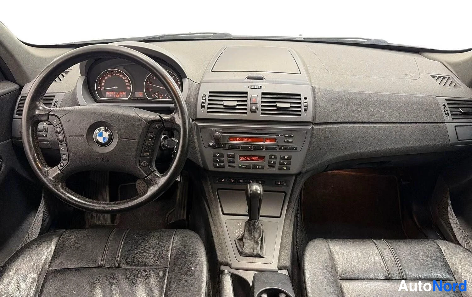 Muu: Ohjaamo etupenkkien takaa: BMW-ratti, mittaristo, keskikonsolin radio ja automaattivaihteen valitsin.