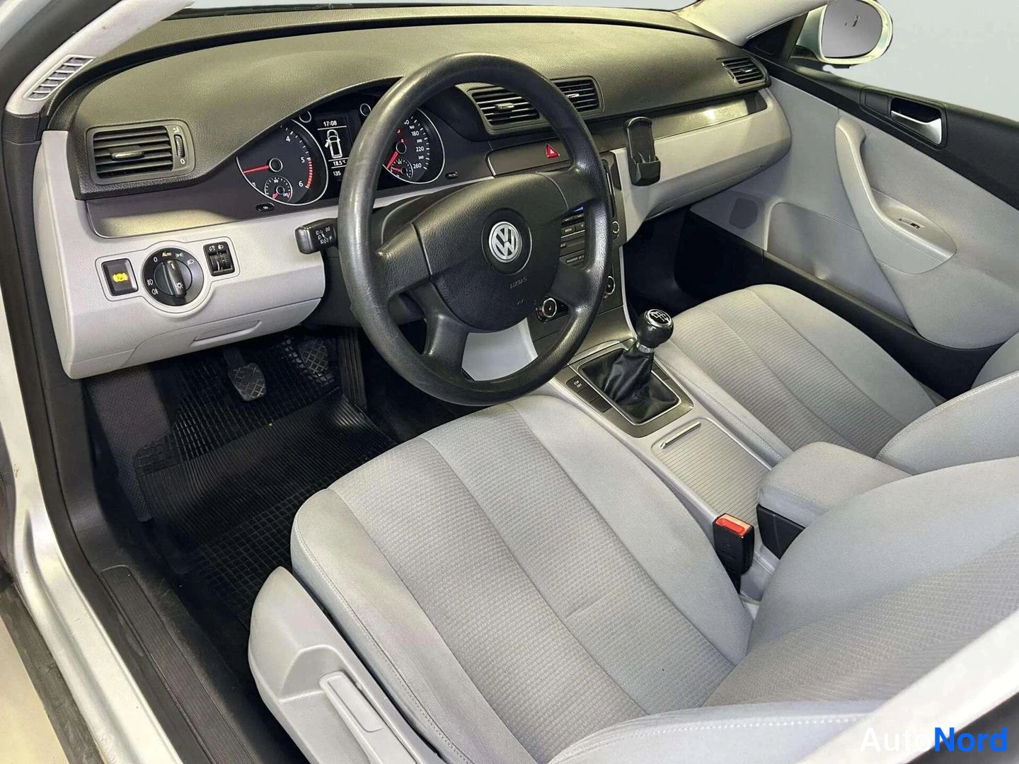 Muu: Auton etuistuimilta kuvattu ohjaamo: Volkswagen-ohjauspyörä, mittaristo, manuaalivaihteenvaihtaja ja harmaat kankaanistuimet.