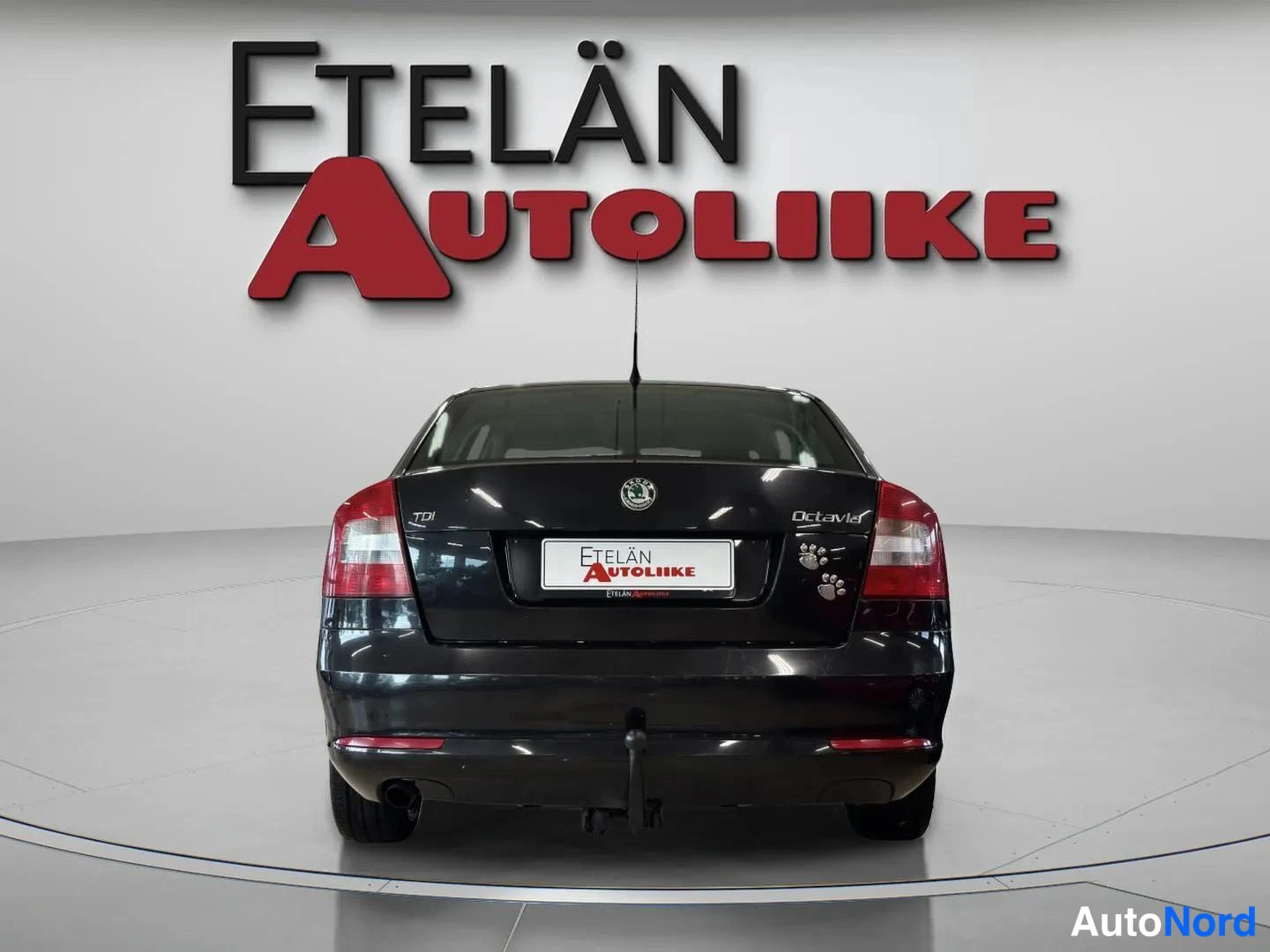 Takaa: Auton takaosa suoraan takaa; kannessa TekstiEtelän Autoliike ja takavalot näkyvät.