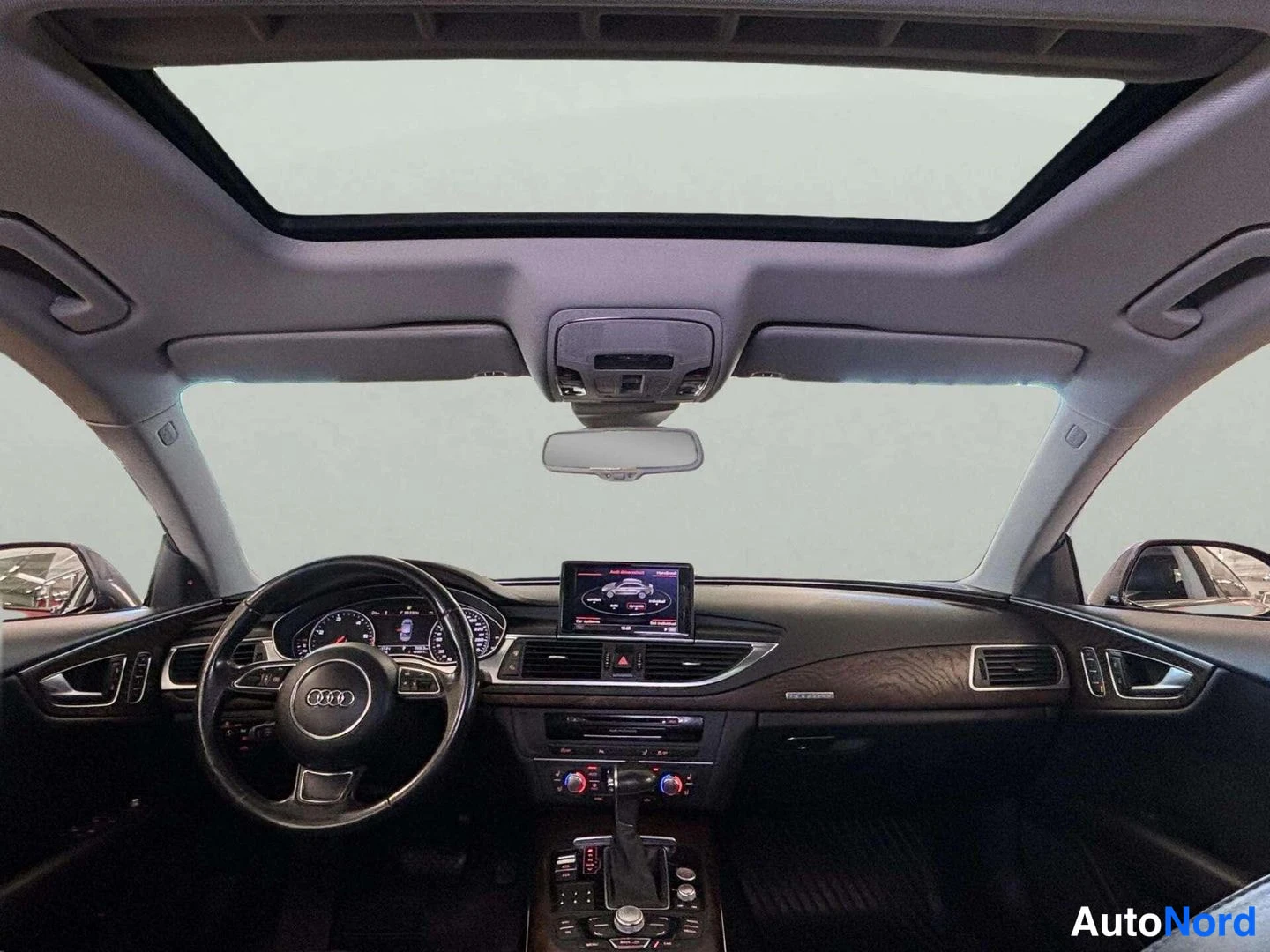 Yksityiskohta: Ohjaamo panoramic-kattoaukosta; Audi-ohjauspyörä, kojelaudan näyttö ja vaihteenvalitsin näkyvät.