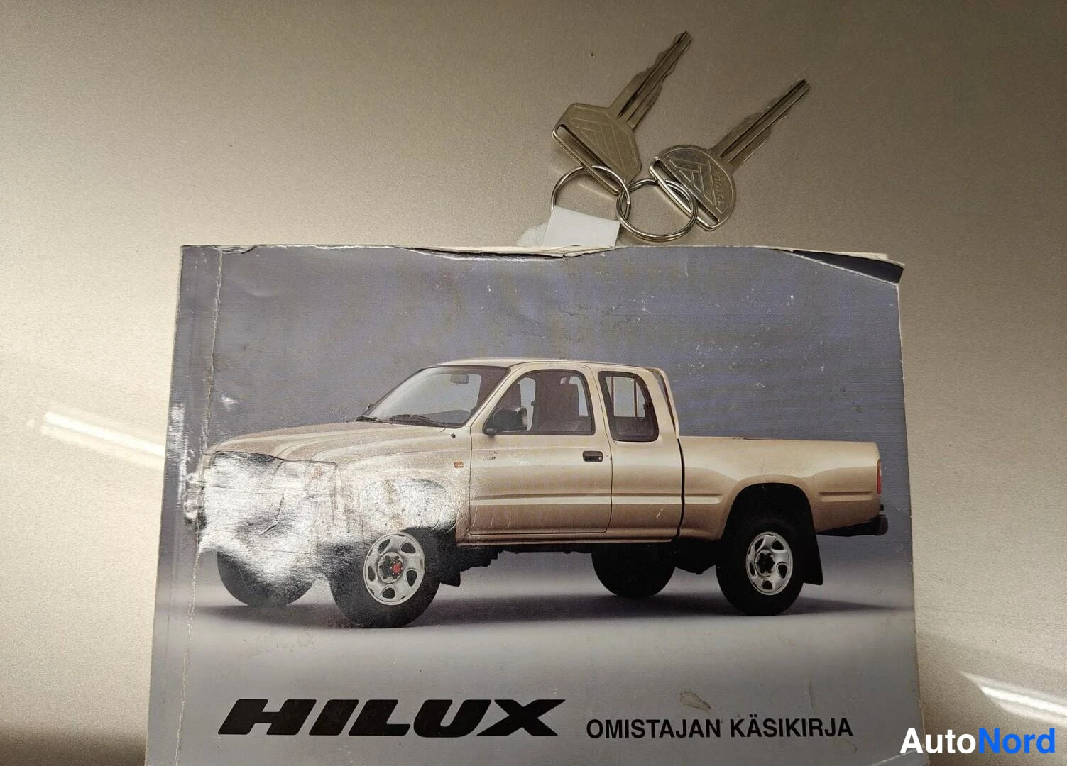 Muu: Toyota Hiluxin omistajan käsikirja ja kaksi avainta