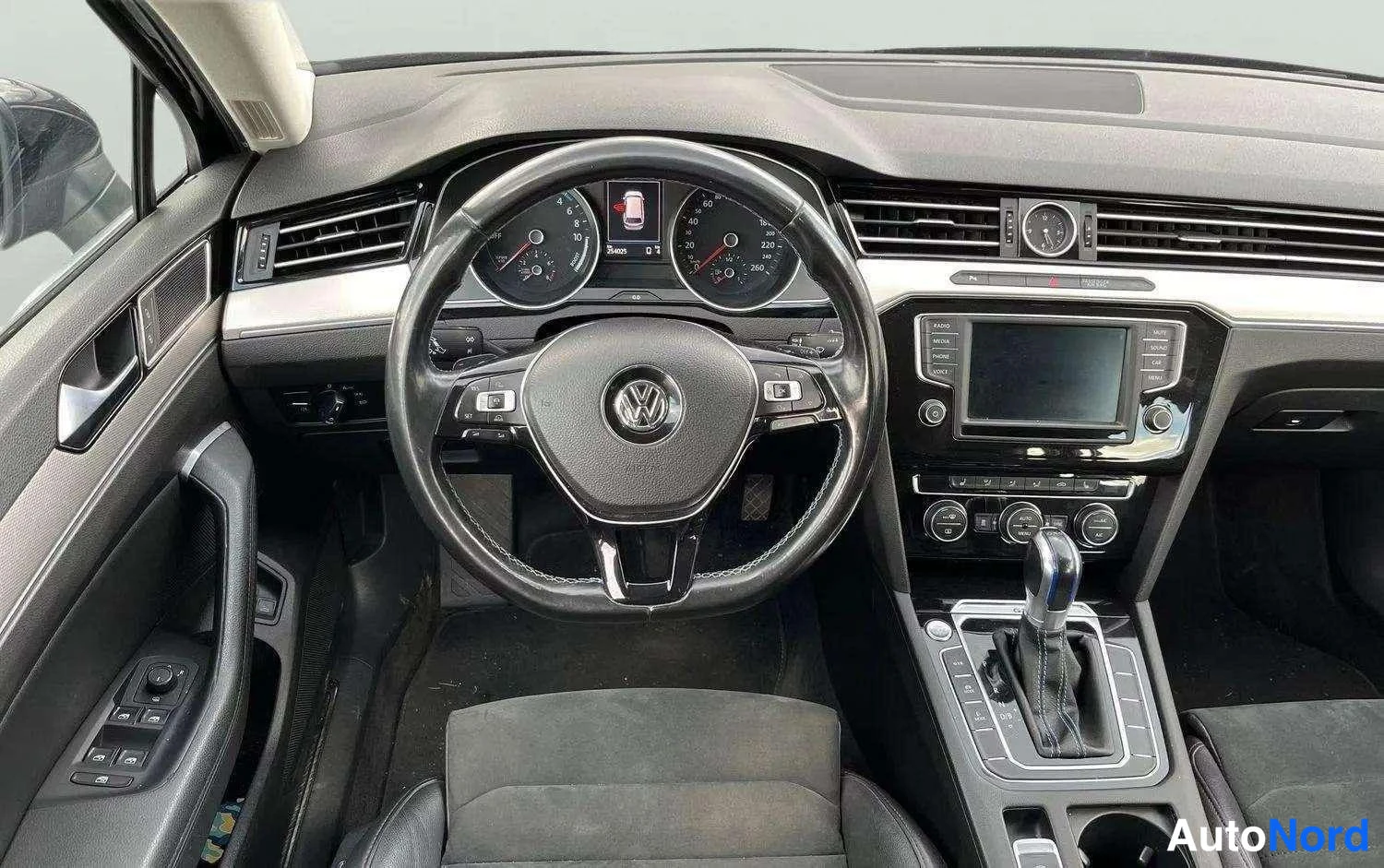 Muu: Volkswagenin ohjaamo kuvattuna takaapäin: ohjauspyörä, mittaristo, keskikonsolin näyttö ja automaattivaihteen valitsin.