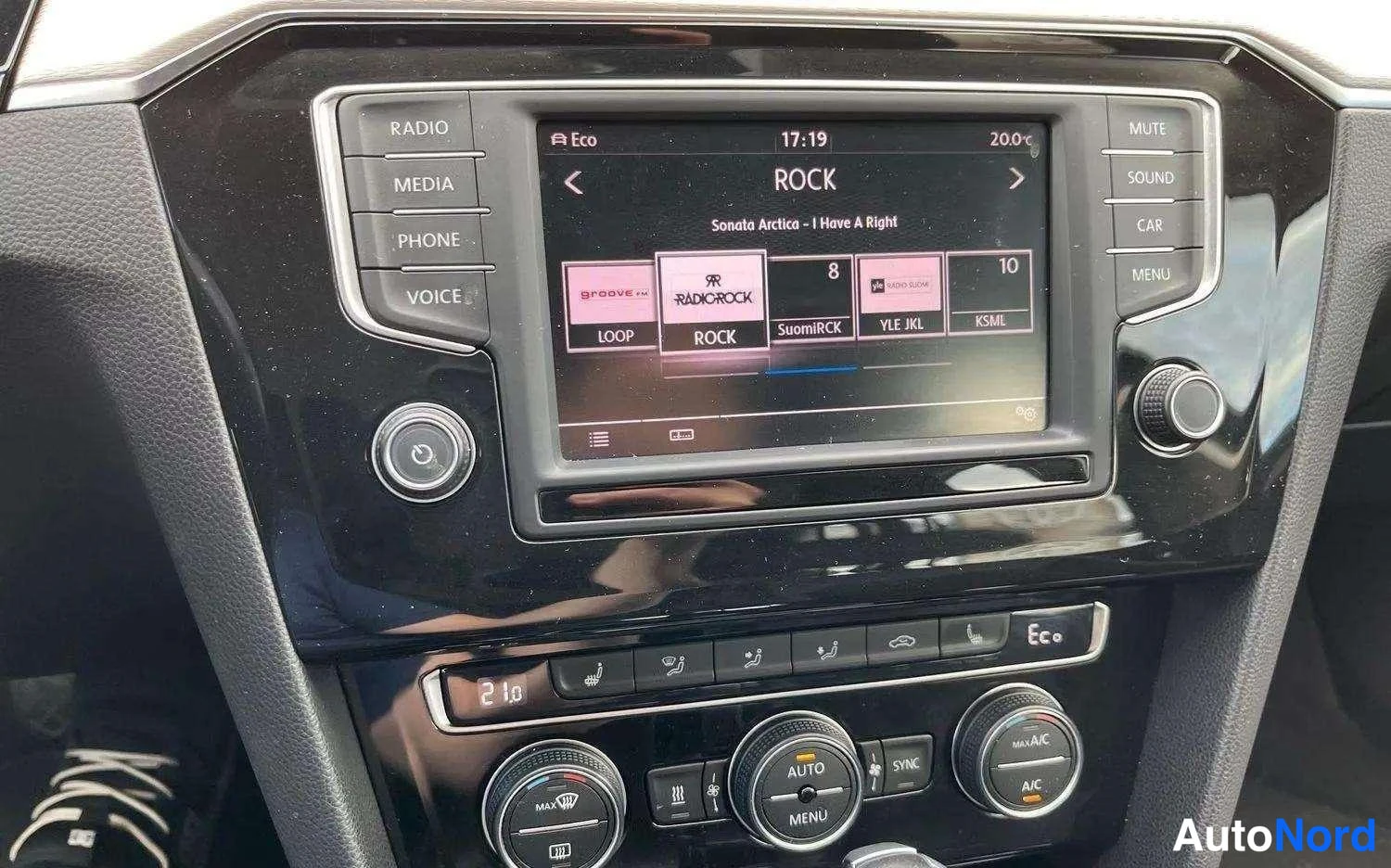 Muu: Keskikonsolin infotainment-näyttö radiovalikossa (ROCK) ja alla ilmastointilaitteen säätimet, kuten AUTO- ja MAX A/C-napit.