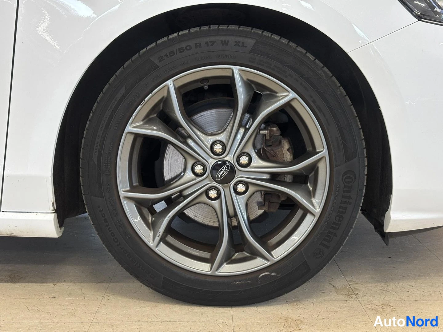 Muu: Lähikuva autorenkaasta ja hopeasta viisipuolisesta vanteesta, rengasmerkintä 215/50 R 17, Continental-teksti rengassivussa.