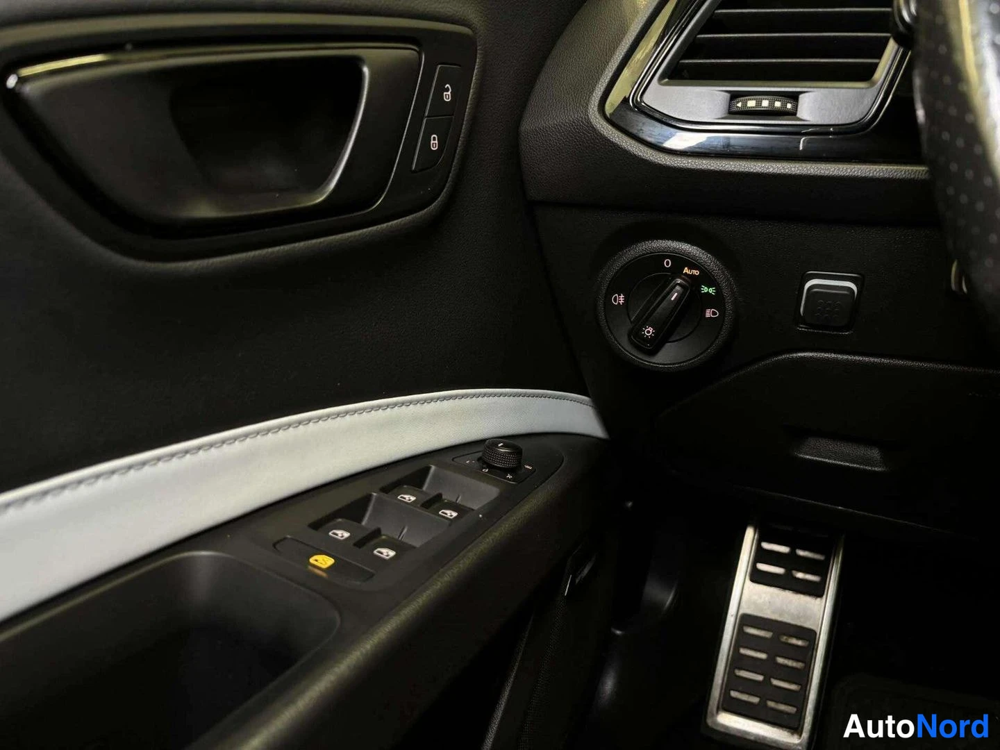 Ohjaamo: Driver's side door panel showing window control switches, lock buttons, and part of the door handle. A light sensor knob is visible on the dashboard edge next t
