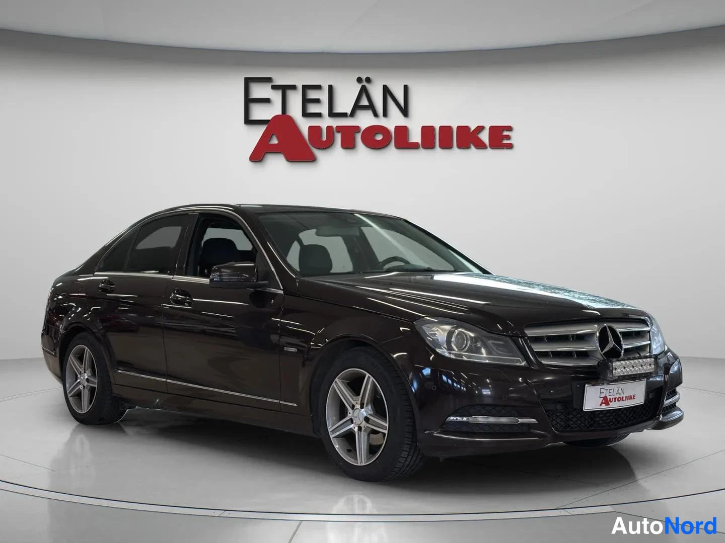 Etuviisto, nokka oikealle: Mercedes-Benz C-sarjan sedanus kuvattu kolmesta neljäsosan etukulmasta; konepelti ja etusäleikkö näkyvät oikealla, auton sivuprofiili vasemmalla. Korin v
