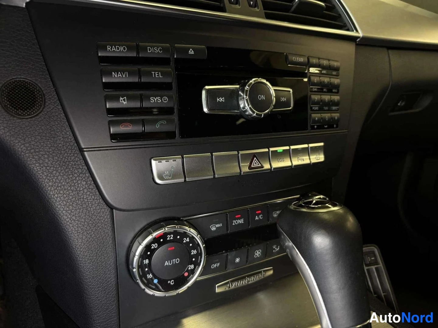 Edestä: Kojelaudan keskiosa: radio-, disc-, navi- ja tel-napit, numeronäppäimistö, ilmastointisäädin (A/C, ZONE, AUTO) ja automaattivaihteen valitsin.
