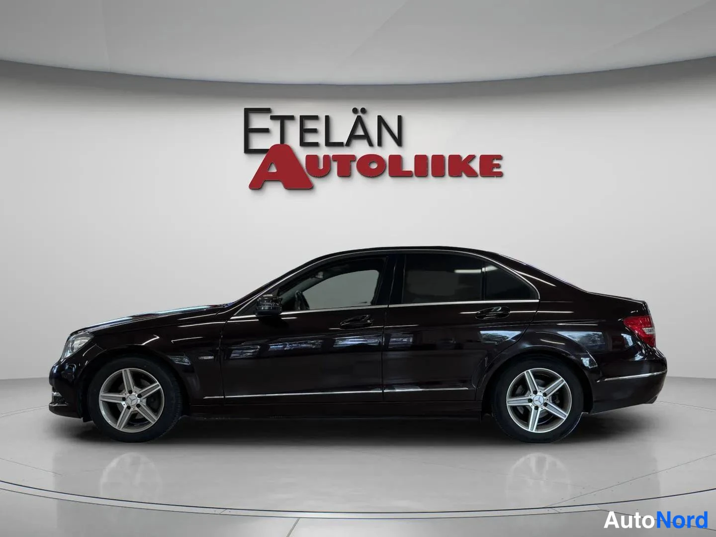 Sivulta: Sivukulmakuvassa Mercedes-Benz C-sedan suoraan sivulta: ovet, ikkunat ja pyörät täyttävät kuvan, kori kiiltävän tummanruskeaa.