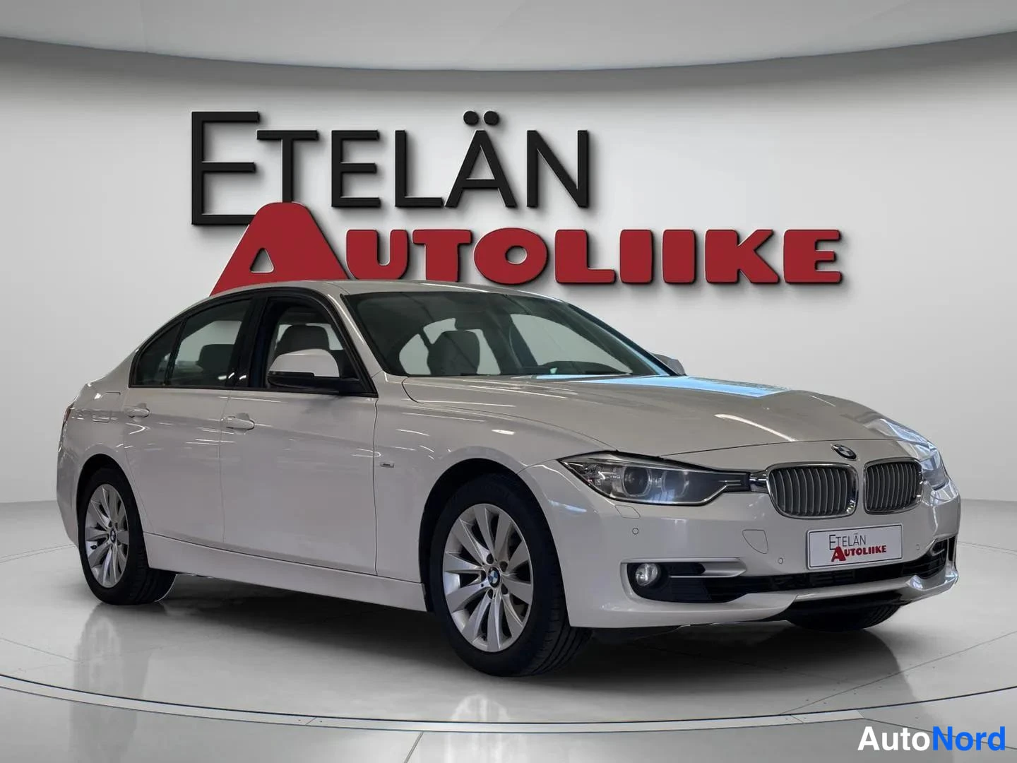 Etuviisto, nokka oikealle: White BMW sedan seen from a front three-quarter view with the nose turned to the right; front grille, headlights and right flank visible
