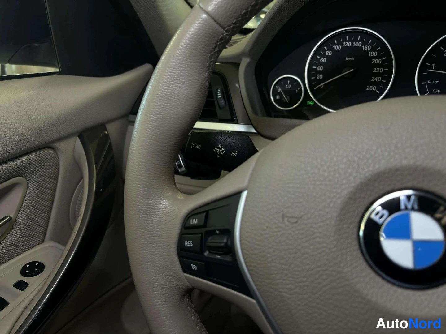 Edestä: BMW-merkkinen ohjaustanko ja kojelaudan mittarit, vakionopeudensäädintalirut ohjaustangossa.