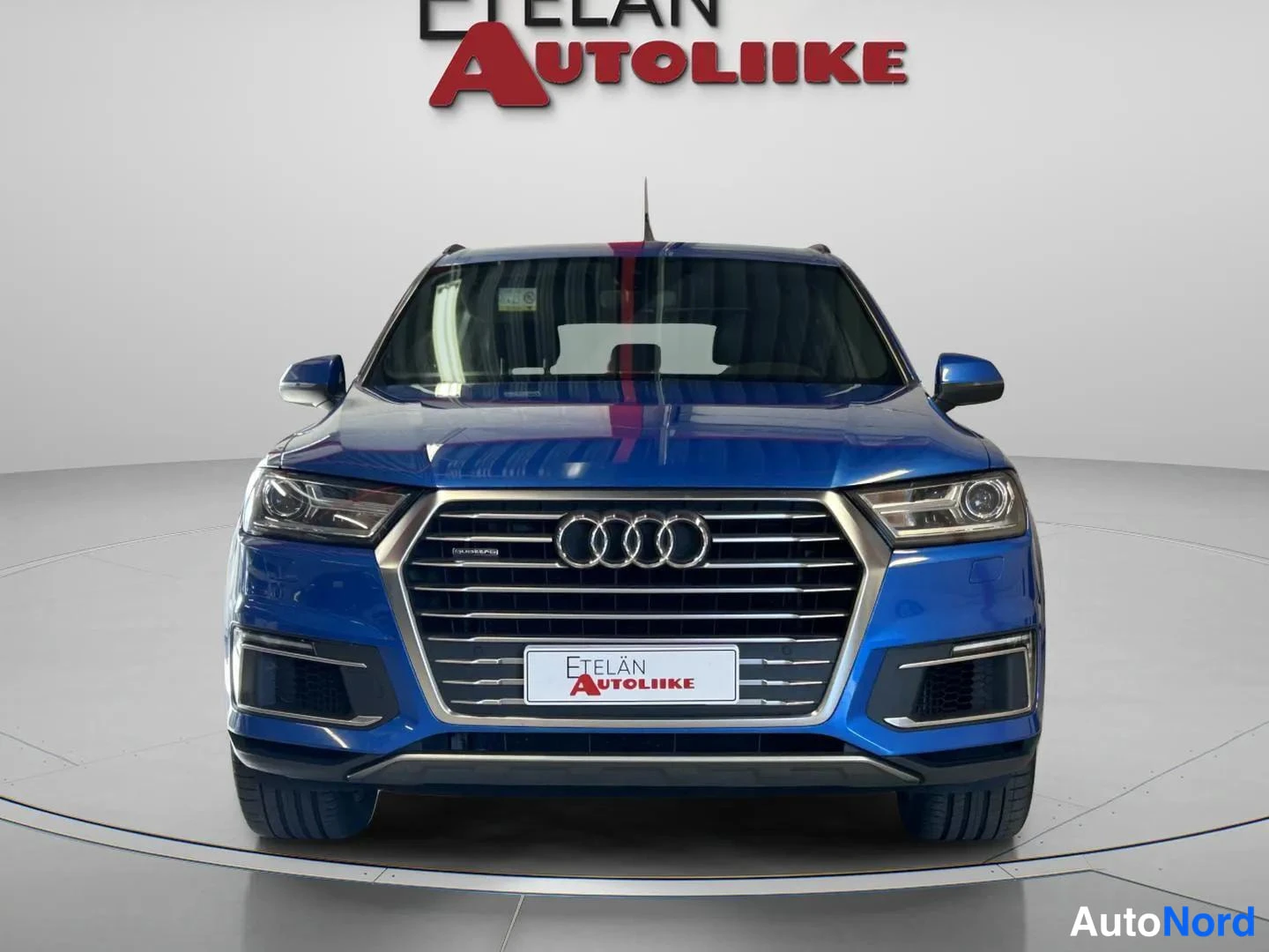Edestä: Sininen Audi Q7 suoraan edestä kuvattuna,ABB-yritys autoliikkeen ETELÄN AUTOLIIKE-logo taustalla.