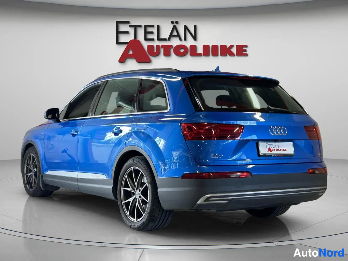 Takaviisto: Sininen Audi Q7 takaviistosta studiossa, Etelän Autoliike -taustalogo.