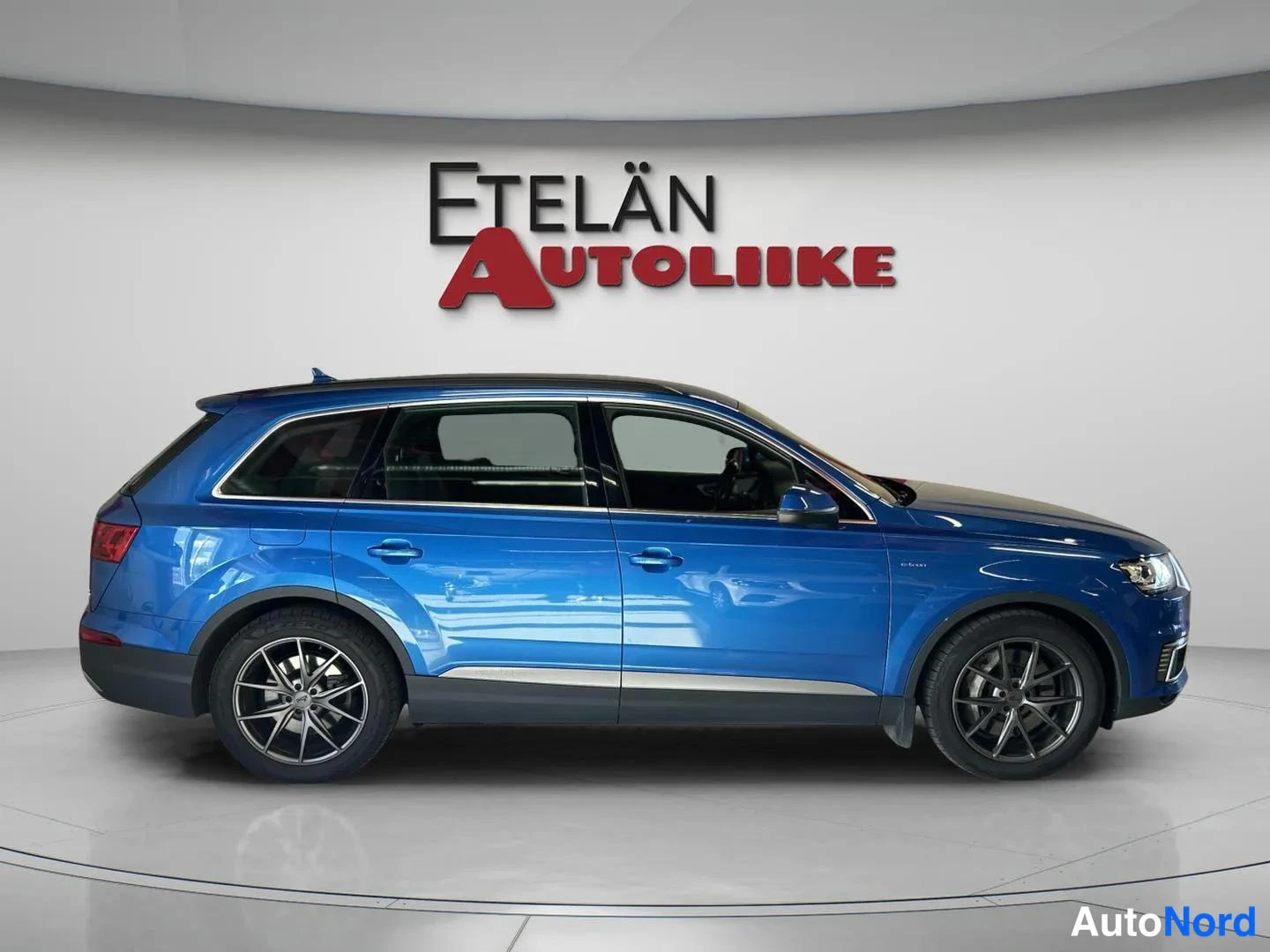 Sivulta: Sininen Audi Q7 sivulta vasemmalta studiossa, Etelän Autoliike -taustalogo.