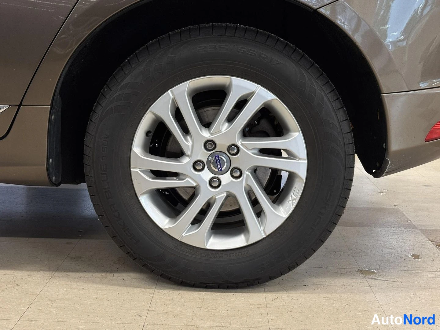 Yksityiskohta: Volvo XC -alumiinivanteen ja 235/65 R 17 -renkaan lähikuva auton pyöränpeltien keskellä; korin väri ruskean pronssinsävyinen.