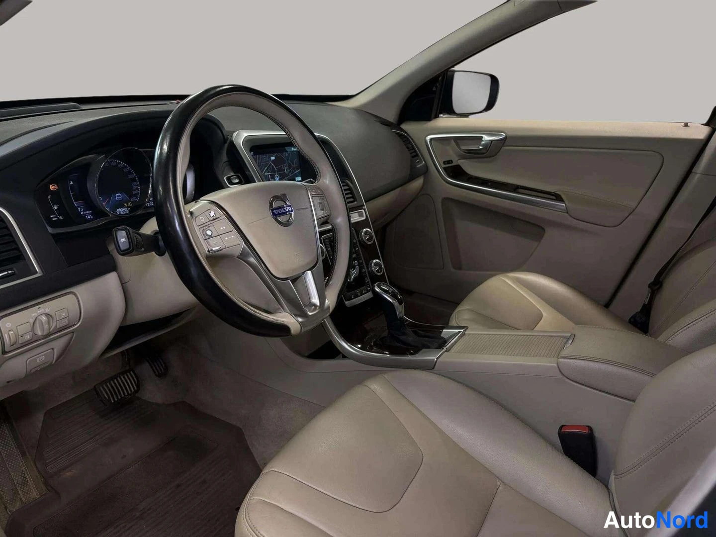 Etuviisto: Auton ohjaamo vasemmalta: beige nahkapenkit, Volvo-ohjauspyörä ja kojelaudan karttanäyttö.