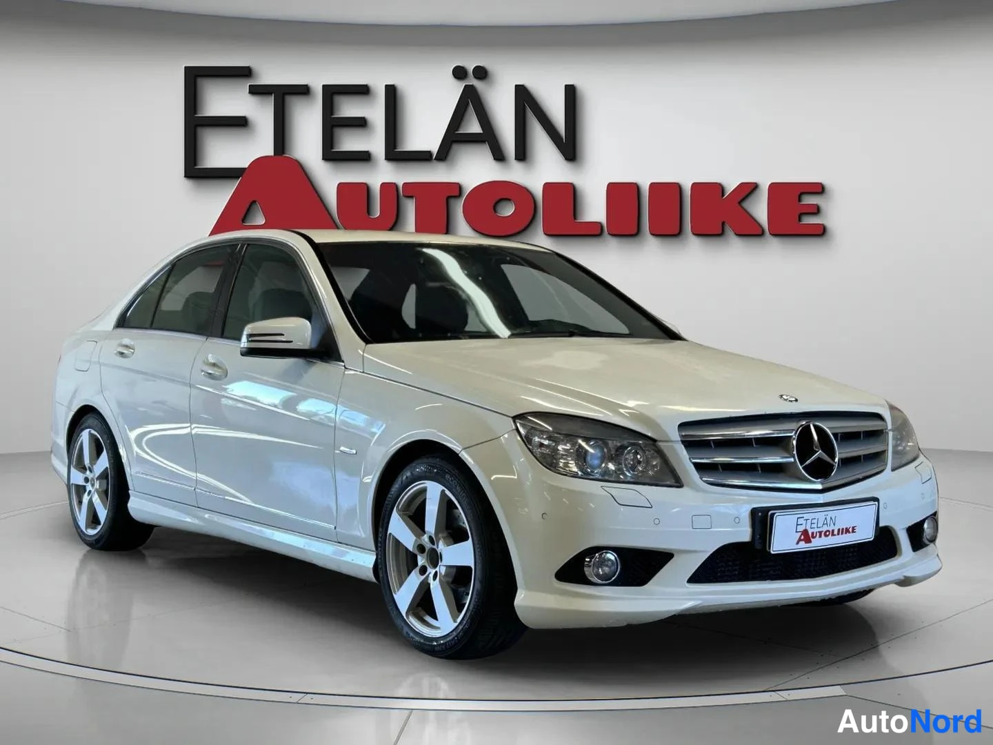 Etuviisto, nokka oikealle: Valkoinen Mercedes-Benz C-sarjan sedan etukulmasta oikealle etelän autoliikkeen studiofinnissä.