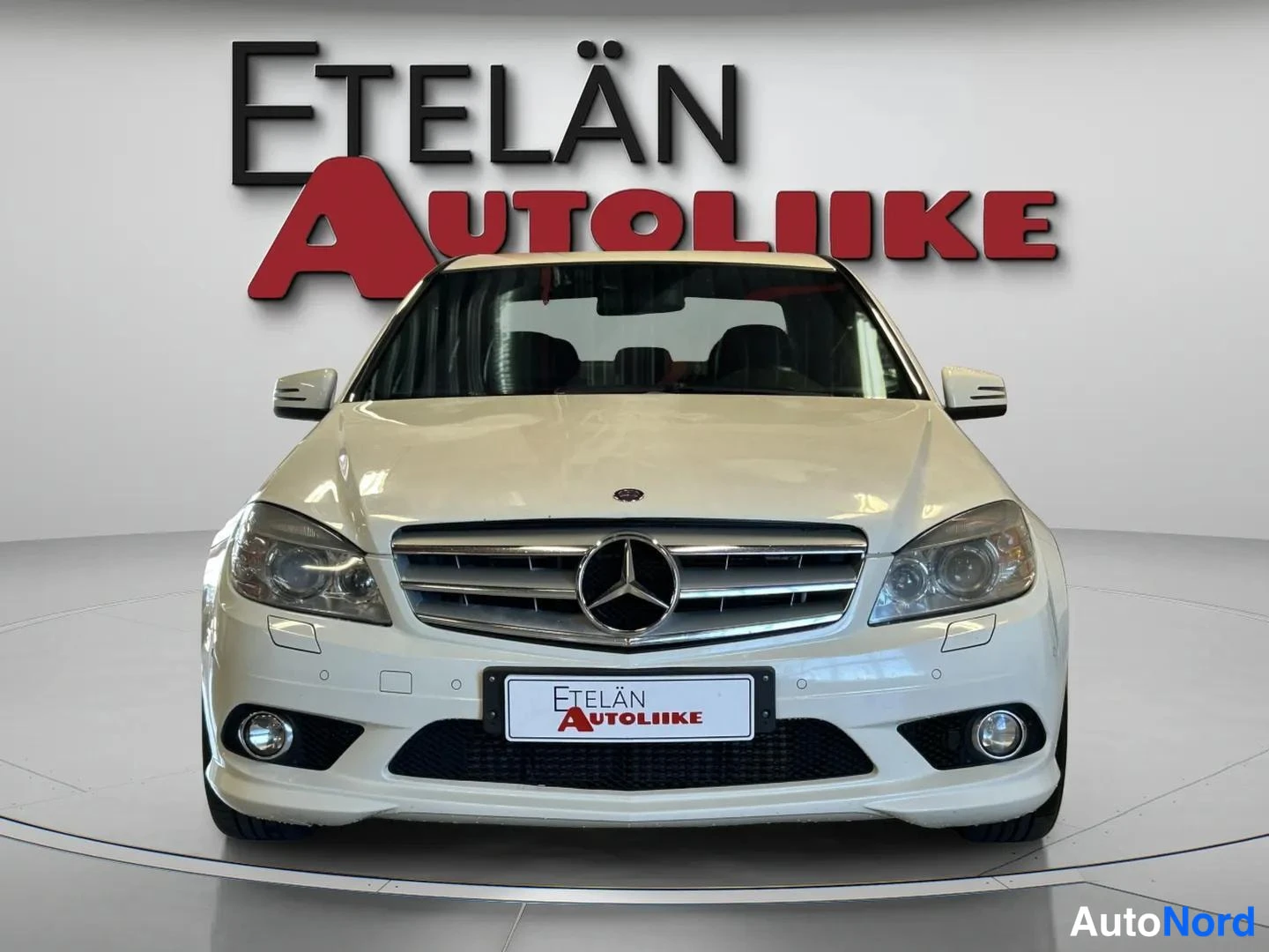 Edestä: Mercedes-Benz C-sarjan sedan suoraan edestä, valkoinen kori ja etusäleikkö Mercedes-tähdellä.