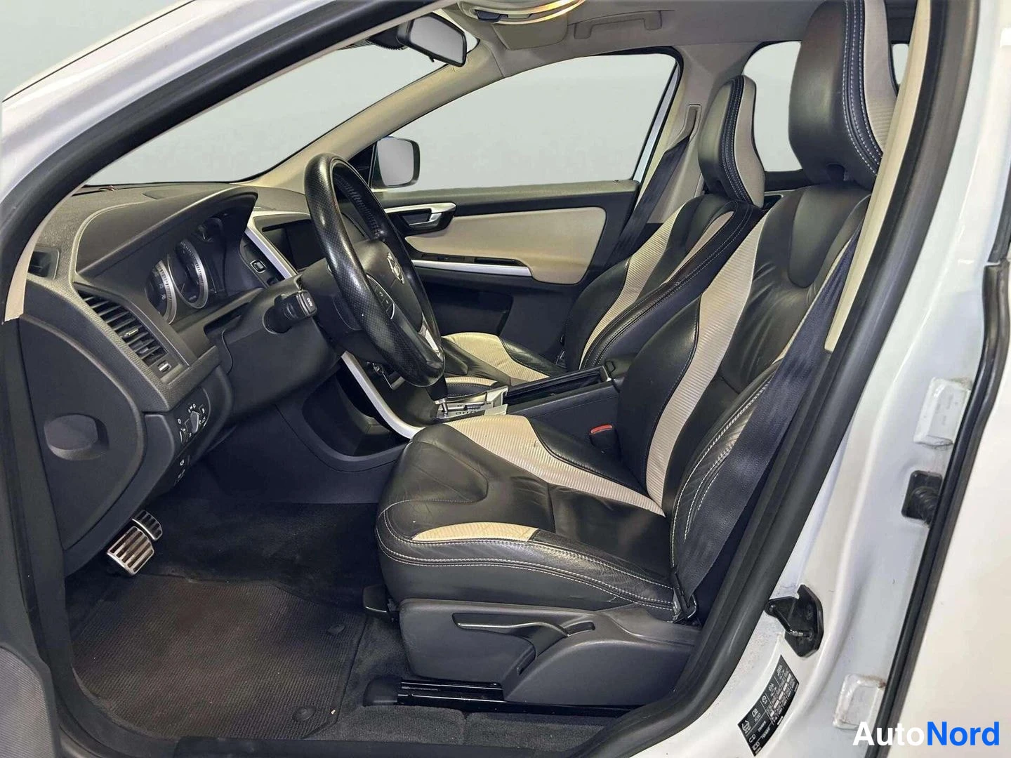 Etuviisto: Volvo XC60:n sisätilat oikeanpuoleisesta ovesta kuvattuna: musta-beiget nahkaistuimet, ohjauspyörä ja automaattivaihteen valitsin.
