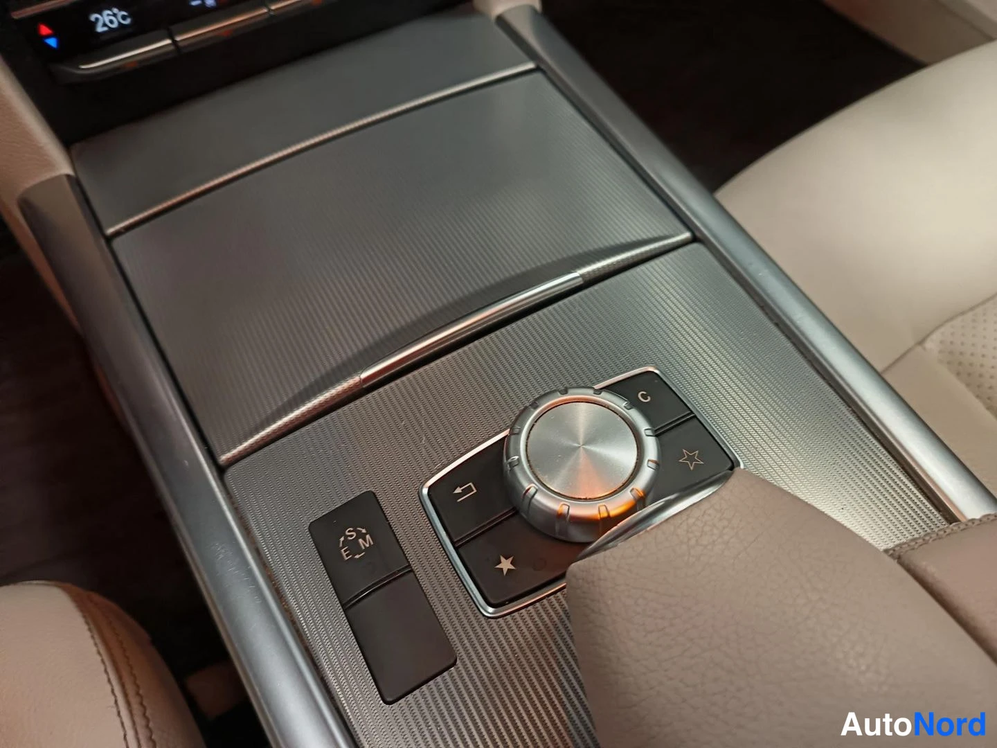 Yksityiskohta: Close-up of the centre console control panel featuring a circular silver rotary selector dial with black function buttons, an S/E/M mode switch on the left and