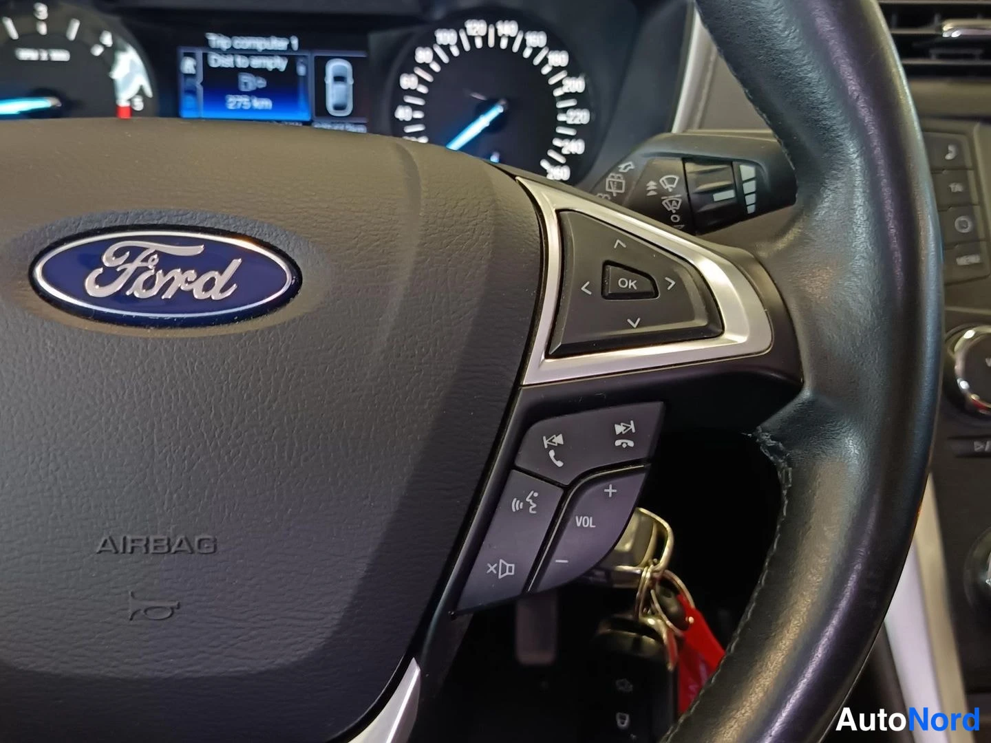 Muu: Ohjauspyörän oikea puoli Ford-merkillä, AIRBAG-teksti ja puhelin-/äänikomennonapit; avaimetvitja roikkuu virtalukossa.