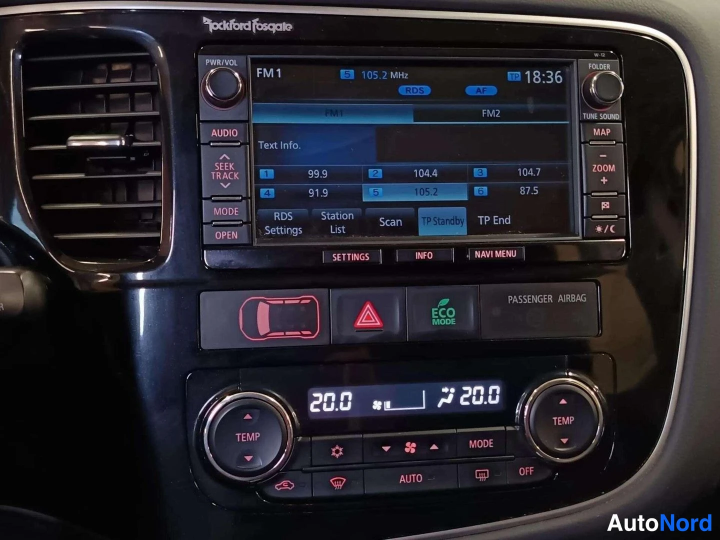 Yksityiskohta: Keskikonsolin sisustuskuva. Keskellä Rockford Fosgate -tietoviihdelaite, jossa näkyvissä radion osoitin FM1 105.2 MHz ja kellonaika 18:36. Laite on ohjaamossa.