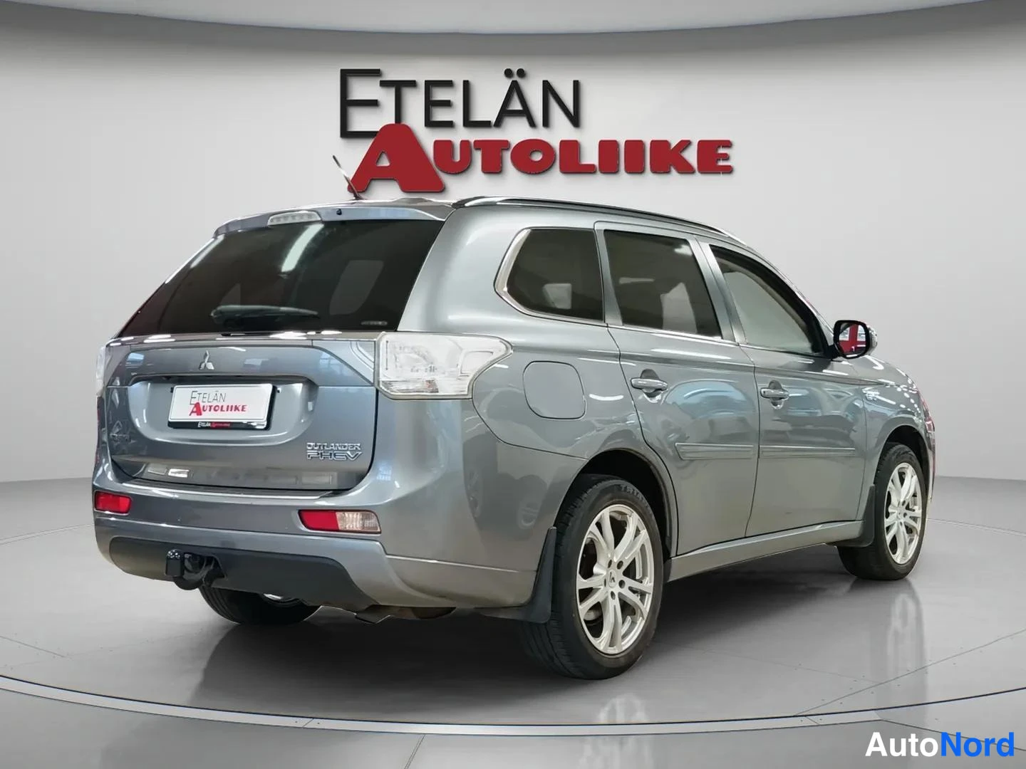Takaviisto: Harmaa Mitsubishi Outlander PHEV takaviistosta kuvattuna, näkyvät takavalot, kylkien ovet ja hopeavanteet.