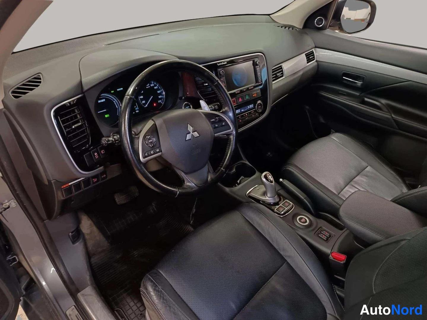 Muu: Auton ohjaamo vasemmalta puolelta: Mitsubishi-ohjauspyörä, hybridin voimansiirtomittari, keskinäytön järjestelmä ja mustat penkit.