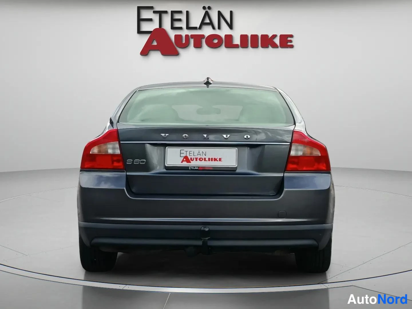 Takaa: Suora takakuva autosta, tummanharmaa sedan, VOLVO- ja S80-tekstit takaluukussa, punaiset takavalot.