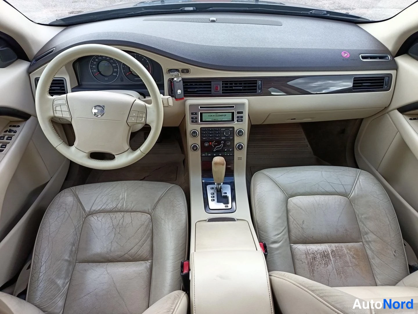 Muu: Ohjaamosta näkyy kulunut beige nahkapenkit, Volvo-ohjauspyörä CRUISE-näppäimellä ja automaattivaihteiston valitsin.