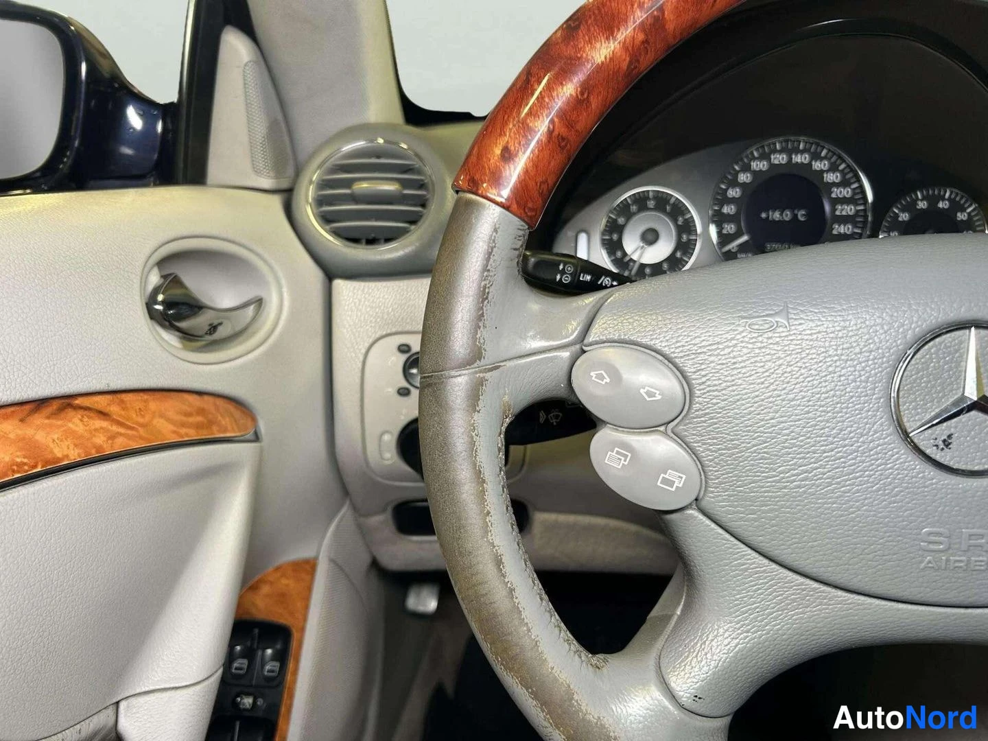 Muu: Kulunut Mercedes-merkkisen auton ohjauspyörä ja instrumenttiryhmä, puukuorista sisustusta ja ilmastointisuuttimia.