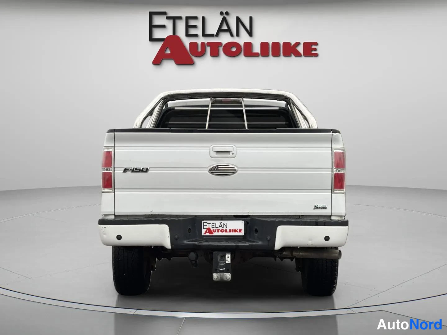 Takaa: Ford F-150 -pickupin takaosa suoraan takaa: valkoinen avolava, F-150-merkintä, takavalojen osat ja Etelän Autoliike-tunnus rekisterinpaikalla.