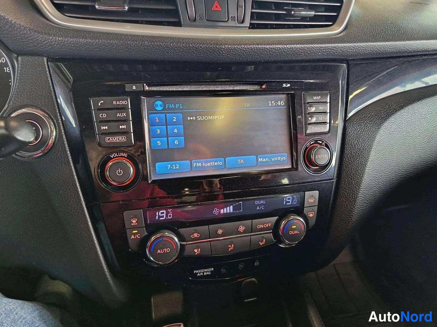 Yksityiskohta: Keskikonsolin lähikuva: radiossa näkyy FM-P1 SUOMIPOP ja ilmastointiaittojen säädöt 19°C, DUAL A/C, AUTO, ON/OFF ja A/C-napit.