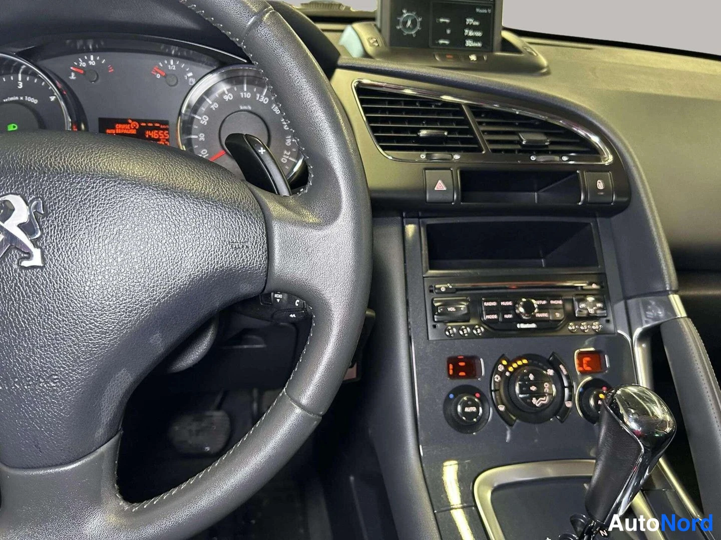 Muu: Auton kojelauta Peugeot-ohjauspyörällä, keskusnäyttö, radio- ja ilmastointipainikkeet sekä automaattivaihteen valitsin