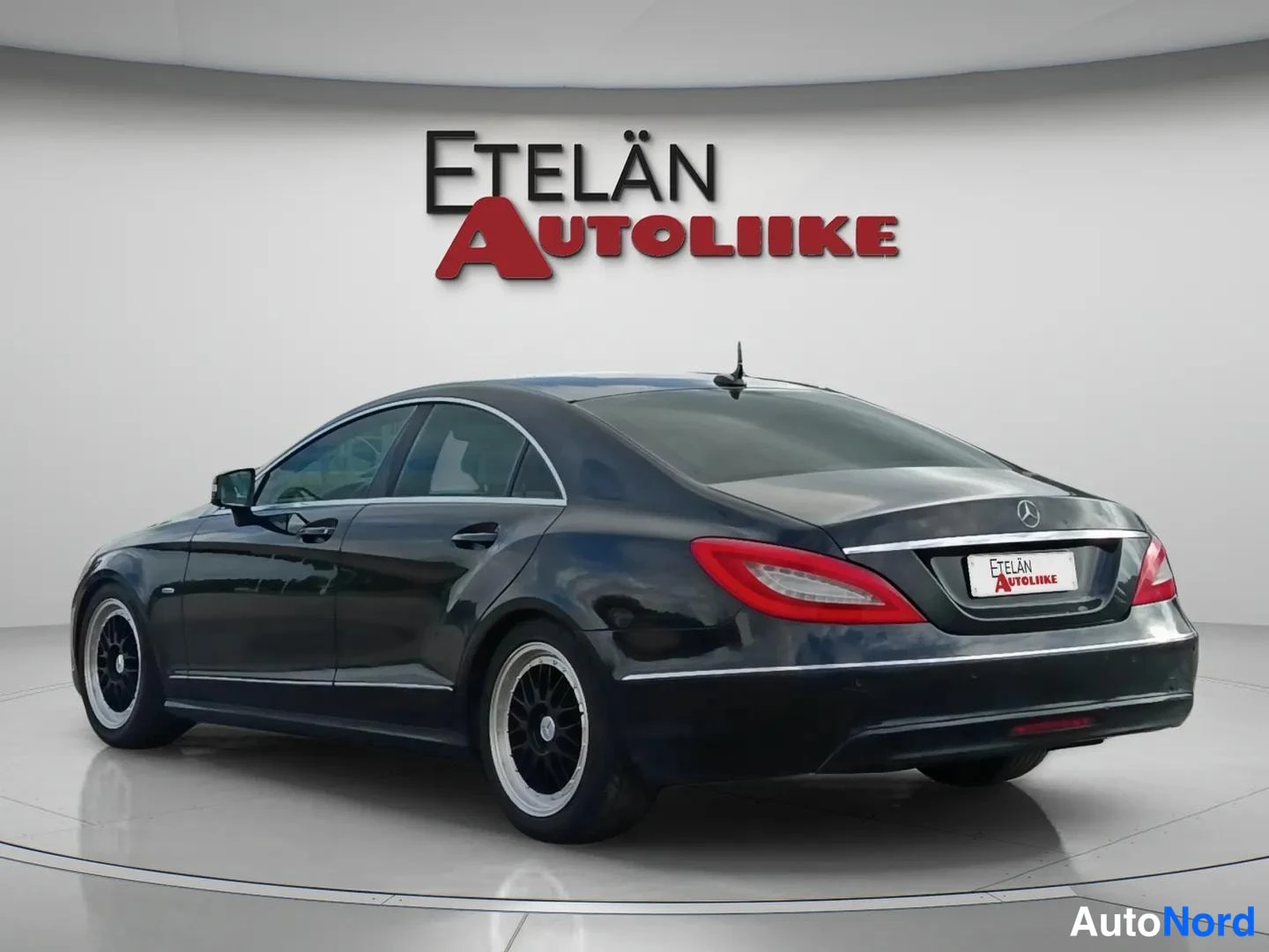Takaviisto: Mustan Mercedes-Benzin takakolmallasivunäyttö vasemmalta, punaiset takavalot ja Etelän Autoliike -kyltti.