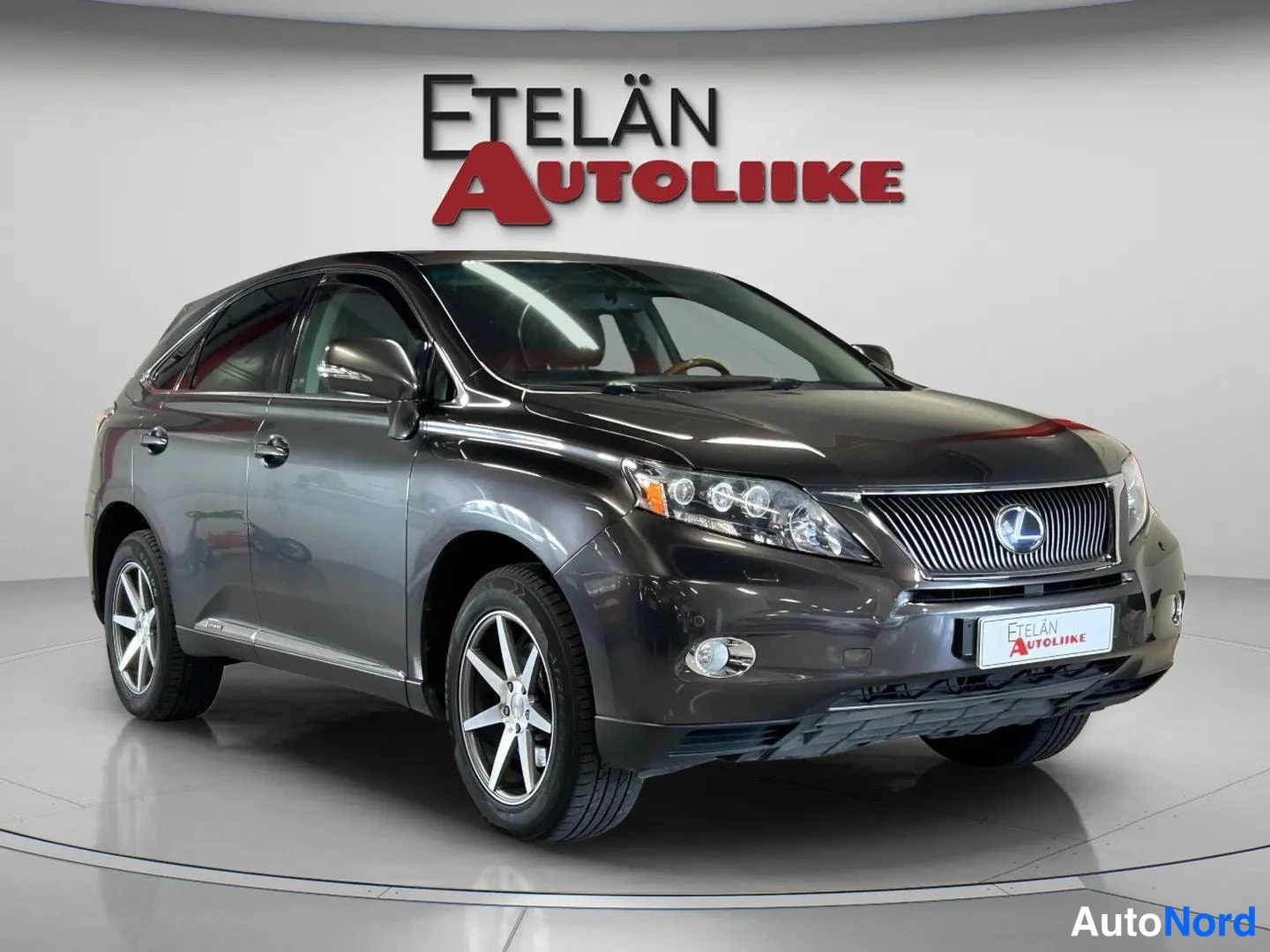 Etuviisto, nokka oikealle: Tummanharmaa Lexus RX -maasturin etukulmanäkymä oikealle kääntyneellä keulalla studiotaustaa vasten.