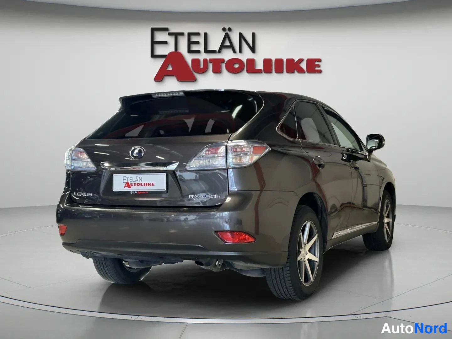 Takaviisto: Tummanharmaan Lexus RX:n takakulma vasemmalta, auton takaosa ja vasen kylki kuvassa.