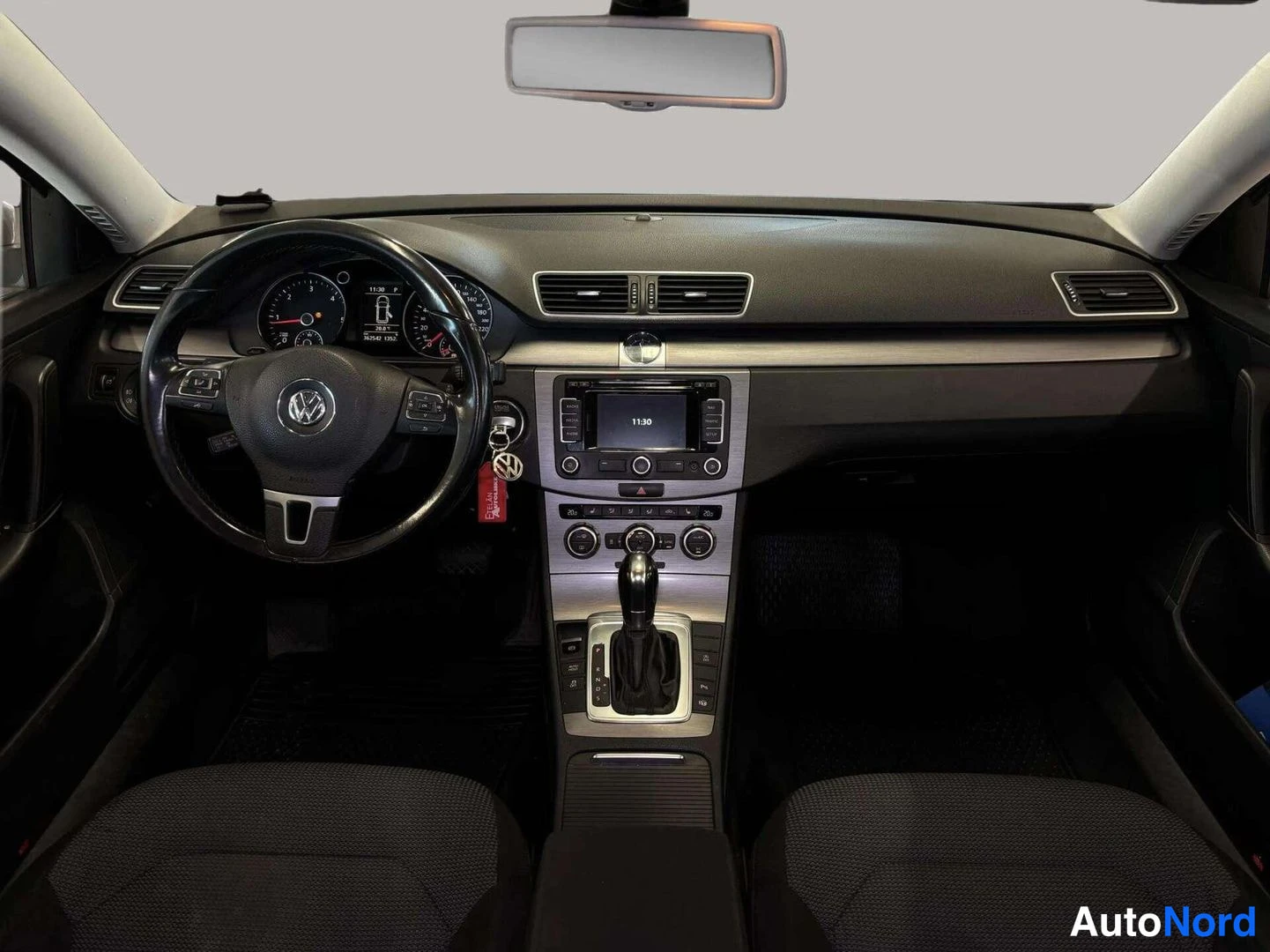 Edestä: Kojelauta suoraan edestä: Volkswagen-ohjauspyörä, mittaristo, näyttö ja automaattivaihteen valitsin.