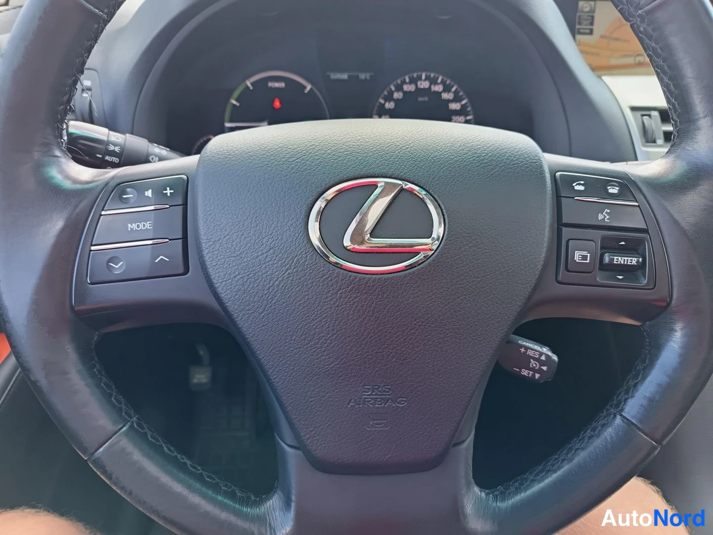 Muu: Ohjauspyörän lähikuva Lexus-merkillä ja monitoiminapit, mittaristo osittain näkyvissä taustalla.