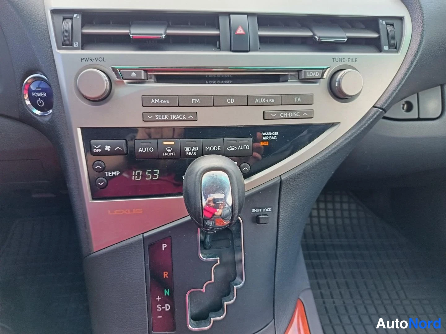 Muu: Auton kojelaudan keskiosa: radio- ja ilmastointipaneeli AUTO-, FRONT- ja REAR-napeilla, lämpötilanäyttö 10:53 ja automaattivaihteen valitsin P-asennossa.