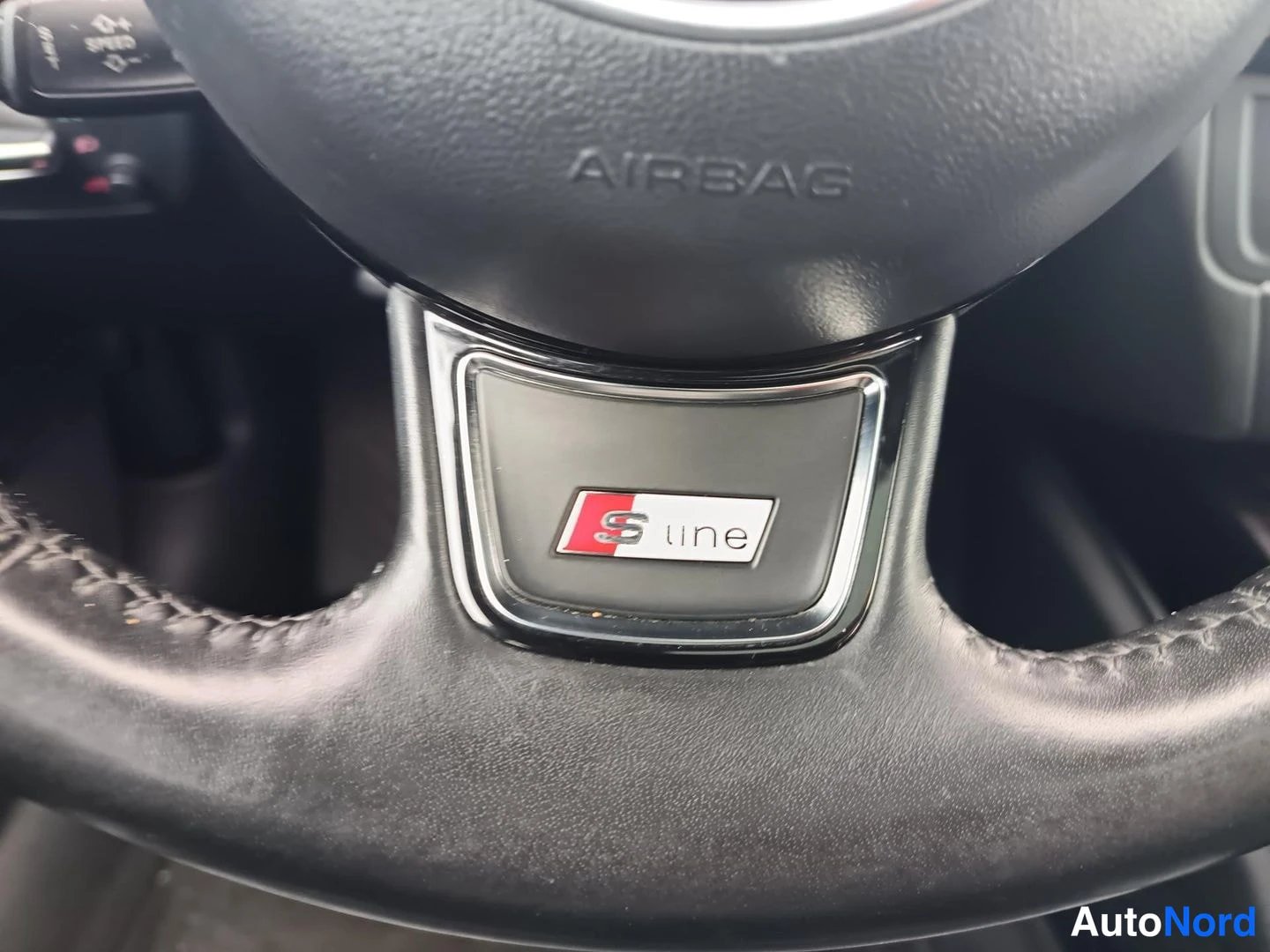 Muu: Audi-ohjauspyörän napatyyny AIRBAG-tekstillä ja S line -embleemillä; nahkaiset pinnat ja ompelukset näkyvät.