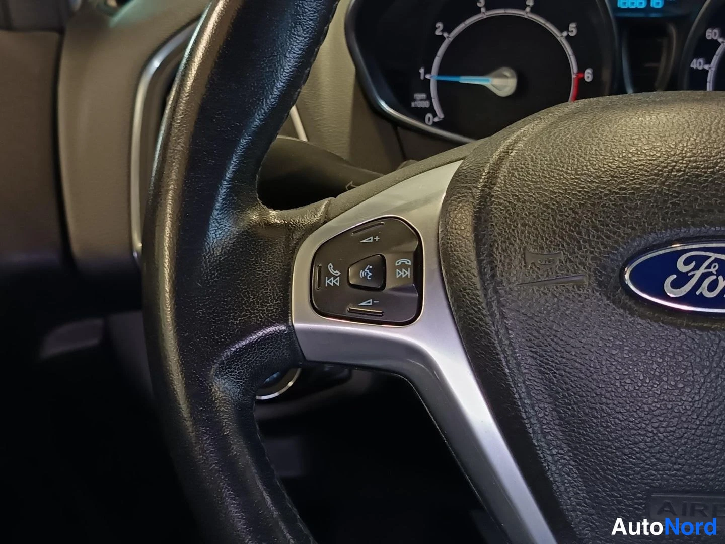 Yksityiskohta: Detailed view of the left side of the steering wheel showing multifunction controls including a phone button and volume buttons mounted on the spoke.