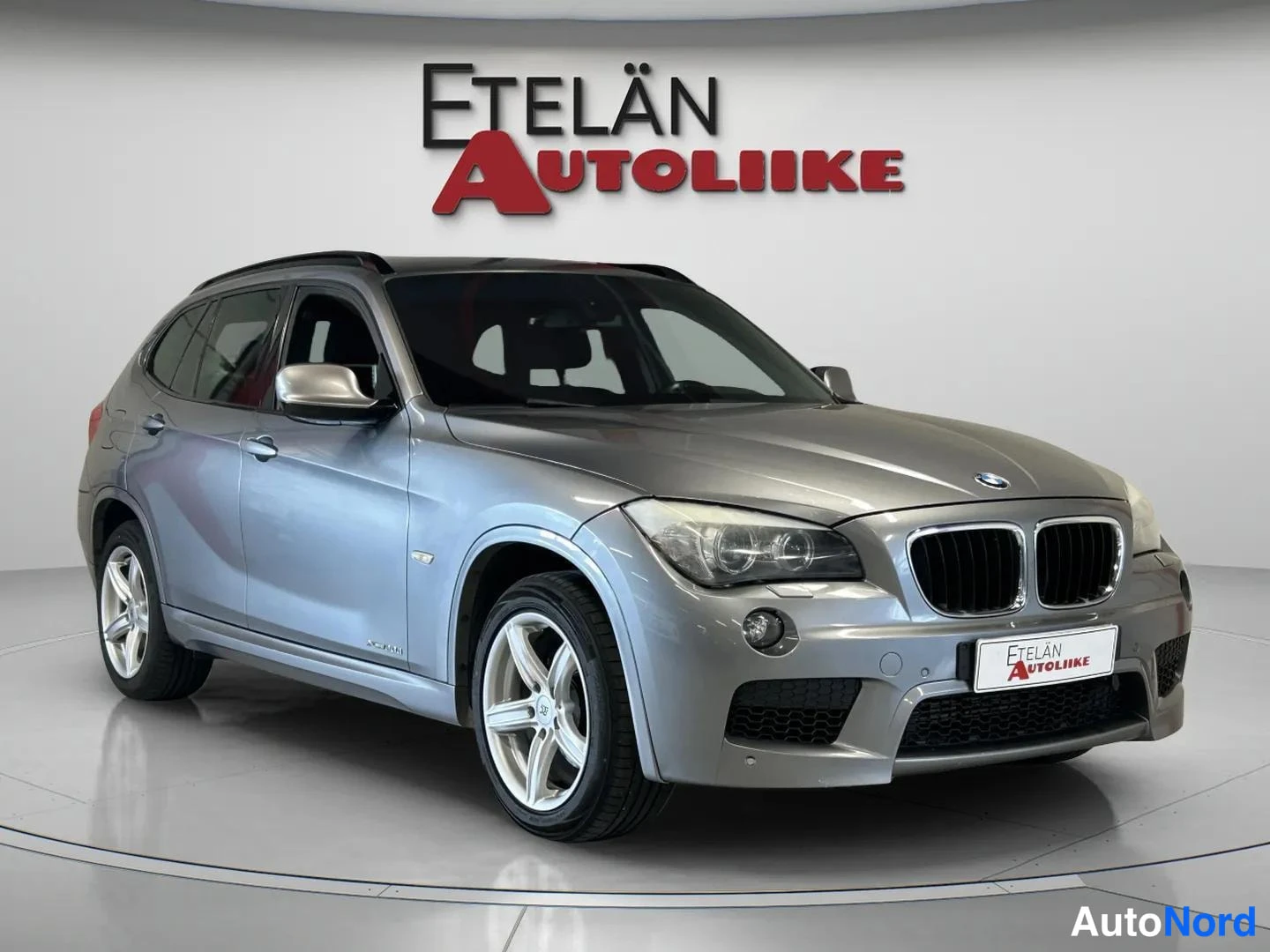 Etuviisto, nokka oikealle: Hopeanharmaa BMW X1 kulmaesitys edestä oikealta, etusäleikkö ja oikea kylki näkyvissä.