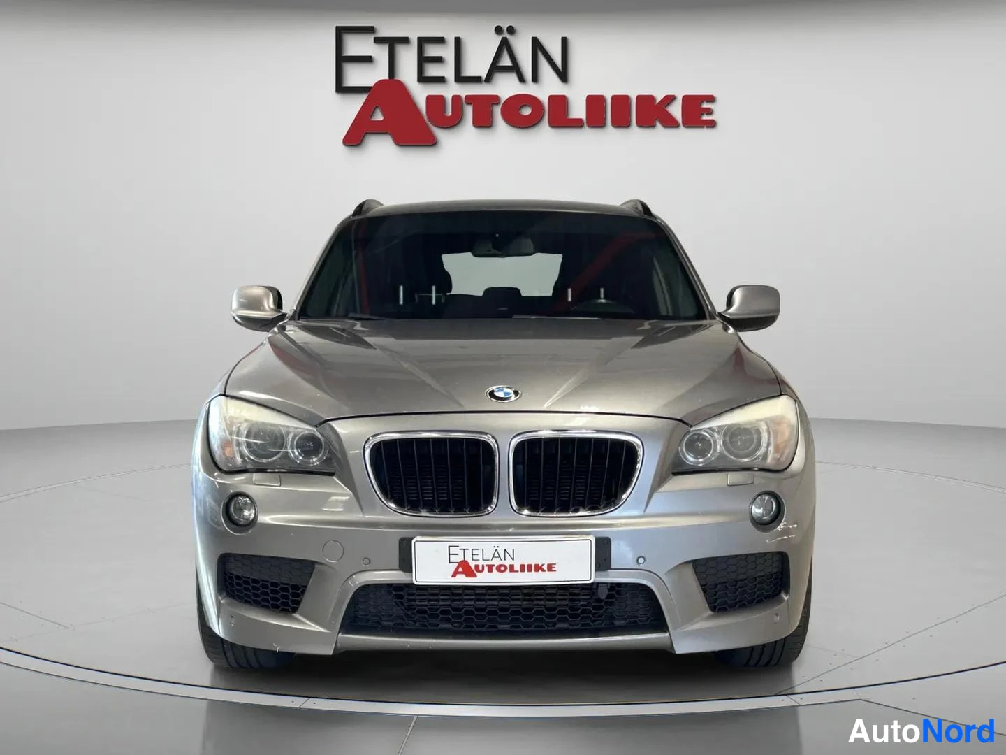 Edestä: BMW:n keula suoraan edestä: munuaissäleikkö, ajovalot ja Etelän Autoliike-kyltti.