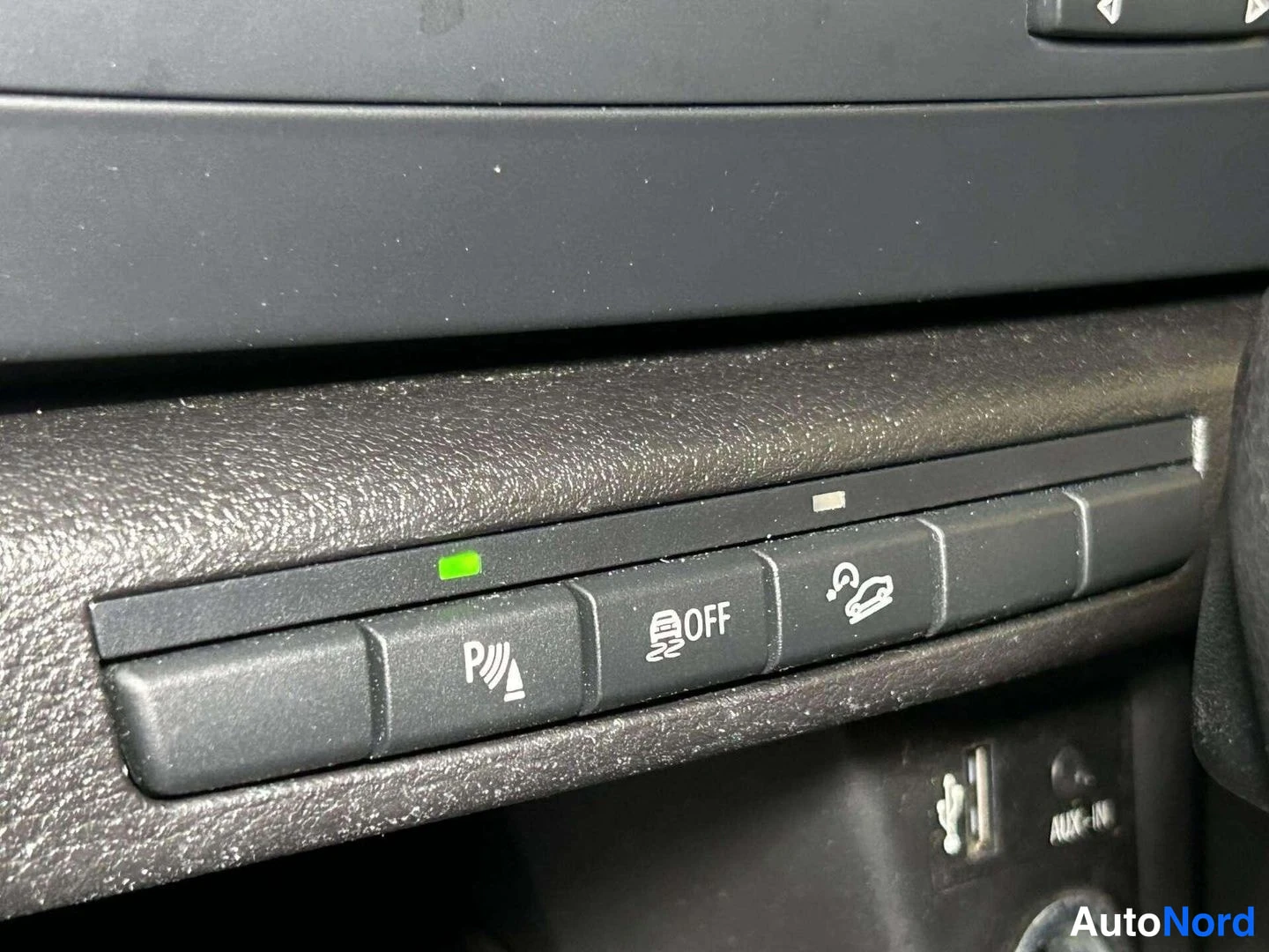 Yksityiskohta: Kojelaudan painikkeet: pysäköintianturin P-merkki, sensorin OFF-painike ja ajovakauden symboli, alla USB- ja AUX-IN-liitännät.