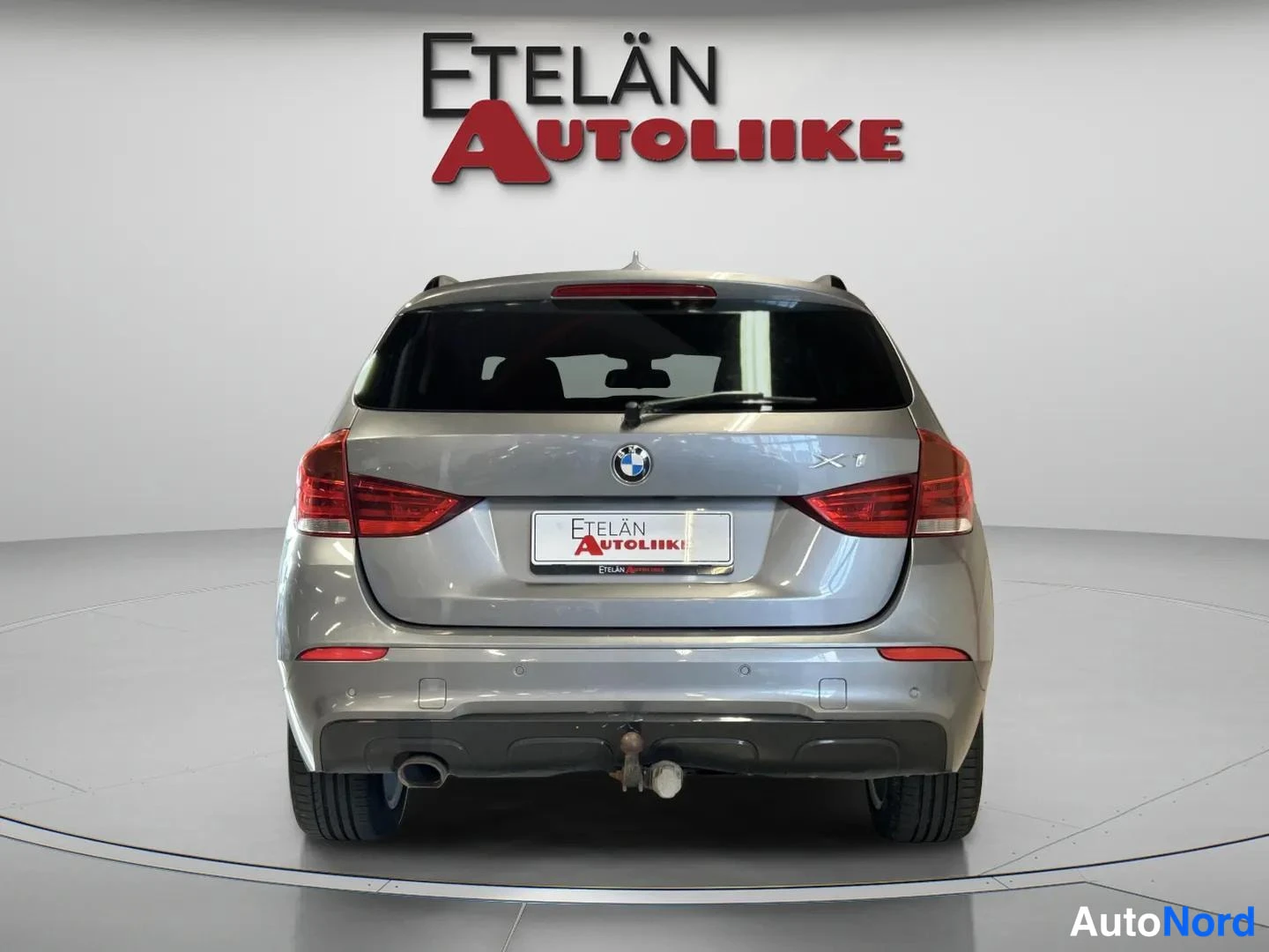 Takaa: BMW X1 suoraan takaa, takavalot, merkkivalo ja kylkiainelpalkki näkyvissä.