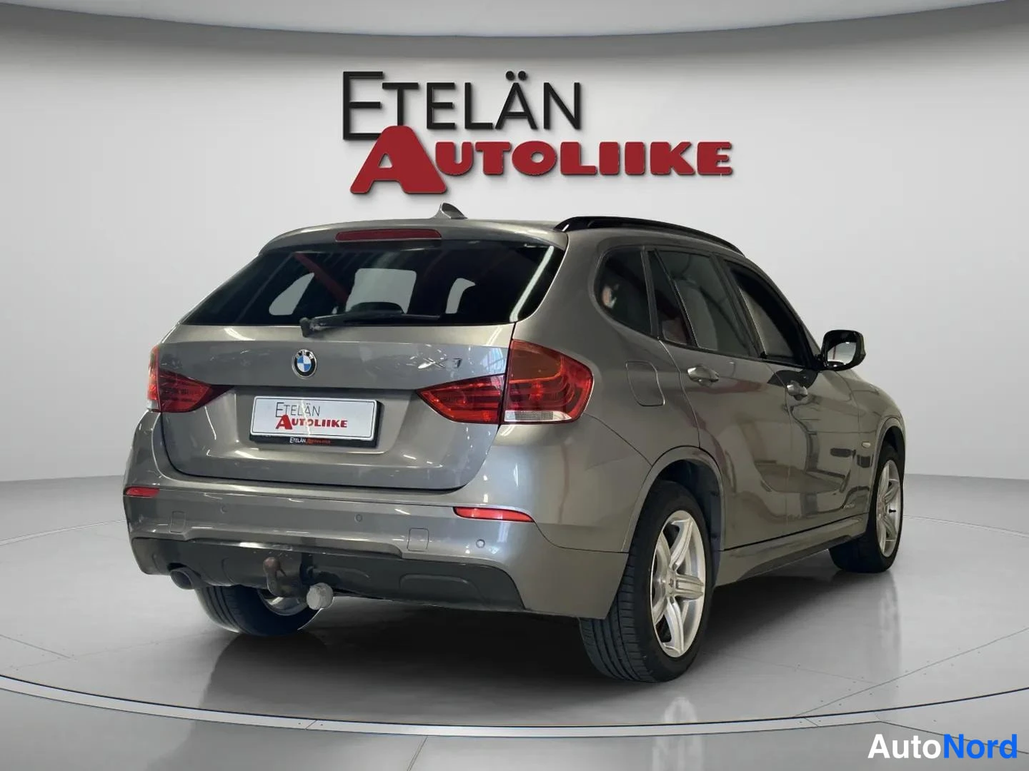 Takaviisto: BMW X1 takaa viistosti vasemmalta, takaosa ja oikea kylki näkyvissä, hopeanharmaa korimaali.